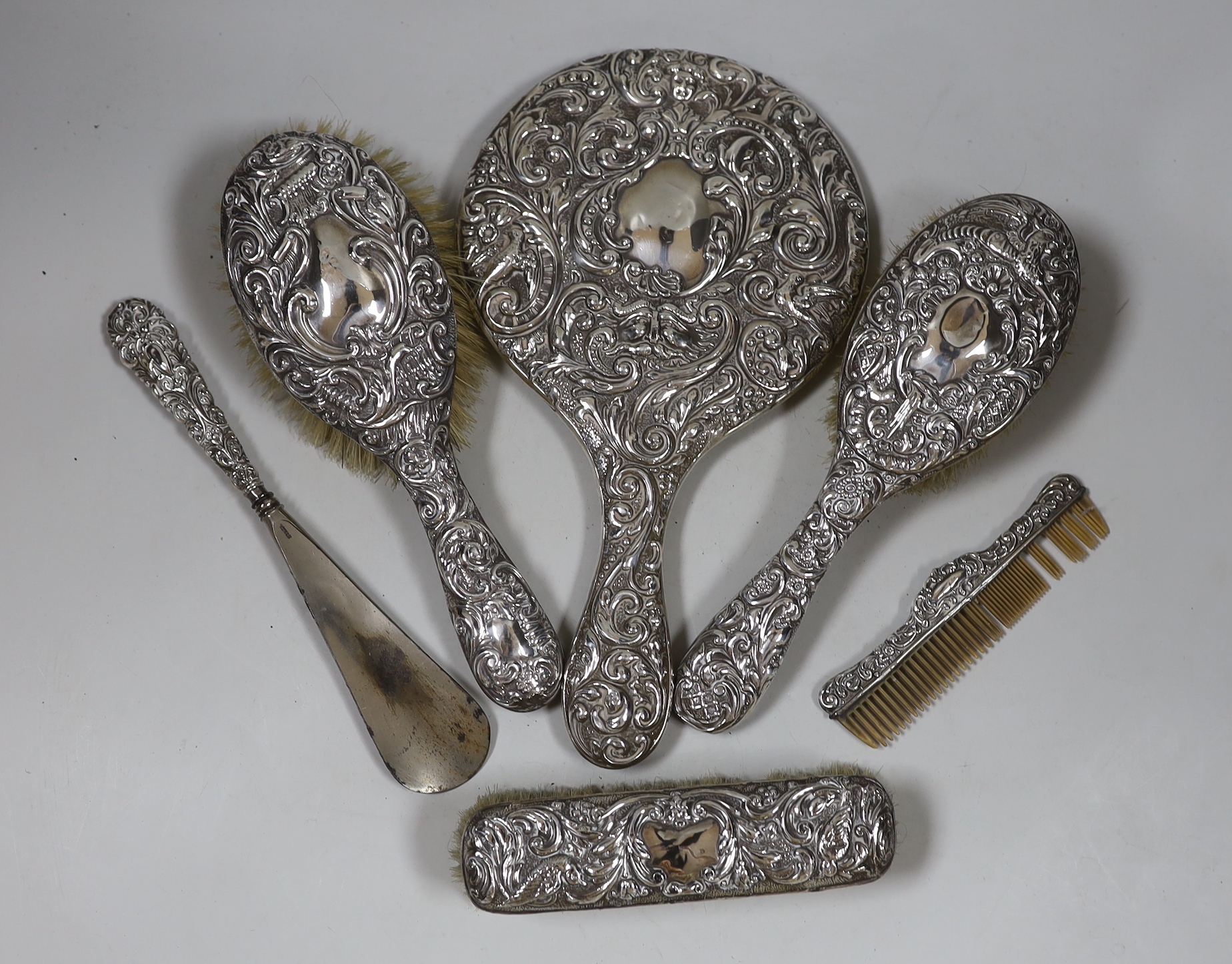 A late Victorian repousse silver mounted six piece mirror and brush set, Chester, 1900.